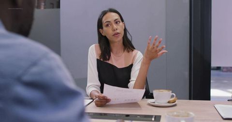 Businesswoman Reviewing Document During Coffee Meeting