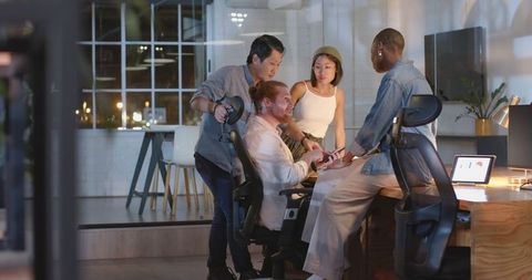 Diverse team celebrating late-night success in modern office