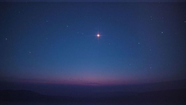 Twilight sky with bright planet and faint stars over hills