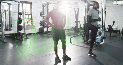 Two male athletes training and monitoring performance analytics overlay in modern gym studio