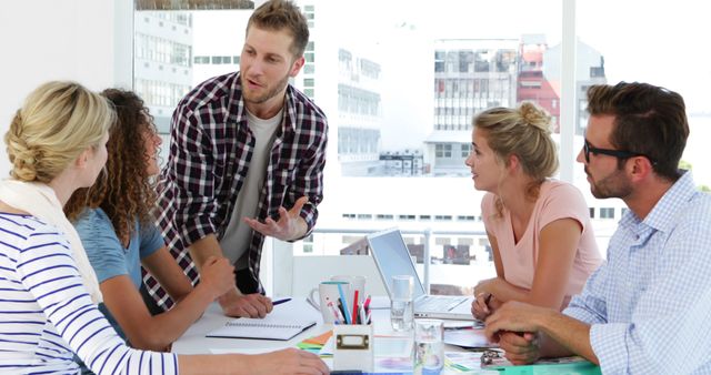 This photo depicts a handsome young male designer passionately explaining his idea in a modern office environment. It illustrates a scene of creativity, innovation, and teamwork as an integral part of the design process. This image is perfect for use in marketing materials for creative companies, educational content surrounding design thinking, articles on modern workplaces, presentations on creativity and collaboration, and promotional content for products targeting design professionals.