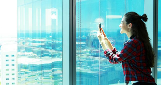 Smiling Woman Taking Photo from Office Window with Phone - Download Free Stock Images Pikwizard.com