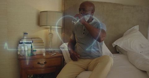 Mature man sipping water on bed with holographic heart pulse overlay for wellness