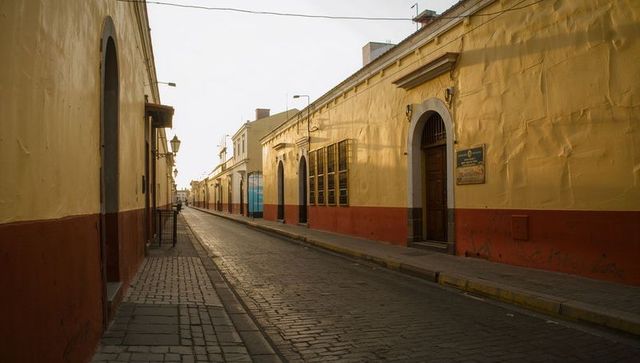 Colonial cobblestone street at dusk leading to vanishing point, arched doors and lanterns