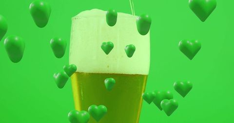 Pouring golden pilsner with foamy head and floating green hearts for festive beer love