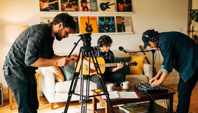 Indie musicians recording live acoustic session in cozy living room home studio