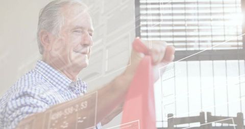 Senior man exercising with red resistance band in sunlit home rehab