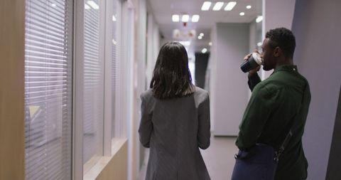 Colleagues Conversing in Office Corridor with Coffee