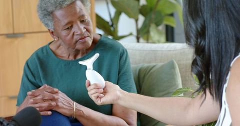 African american senior woman receiving home health device from caregiver