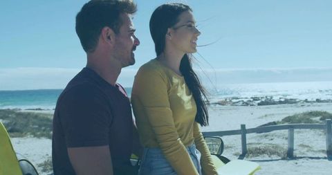 Couple Smiling and Enjoying Coastal Drive on Yellow Vehicle Overlooking Ocean Sandy Beach