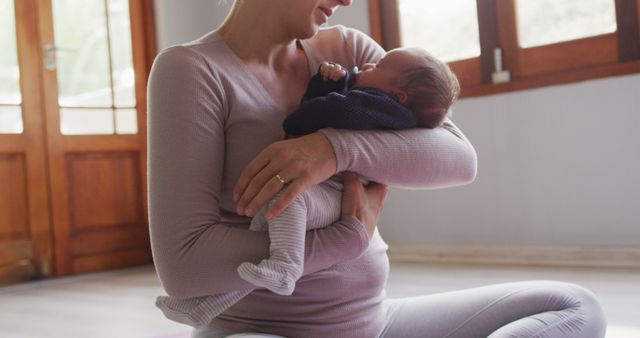 Young mother cradling a newborn baby in a cozy home, emphasizing family love and maternal bonding. Well-suited for topics on motherhood, parenting, family life, and nurturing care. Perfect for articles, blogs, advertising related to maternal health, baby products, and home living.