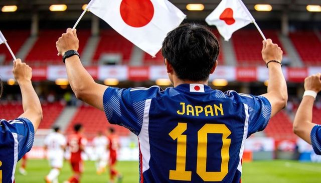 Japanese football supporter waving flags wearing number 10 jersey in packed stadium stands