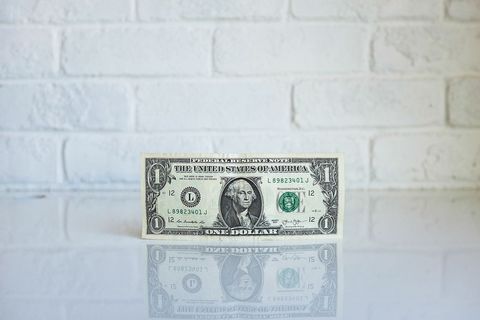 Crisp One Dollar Bill Against White Brick Background
