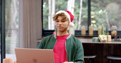Young man in santa hat working on laptop during holiday season