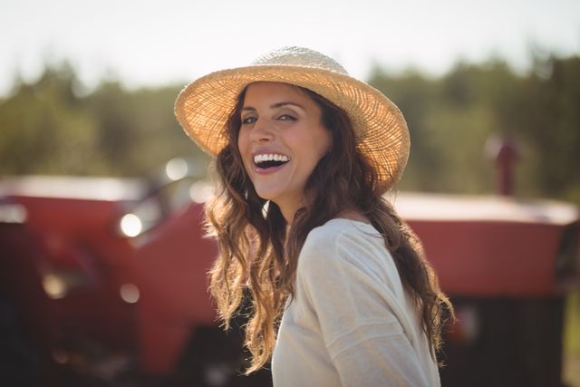 Portrait cheerful young woman wearing sun hat at farm