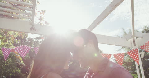 Romantic Couple Smiling Under Sunlight in Garden
