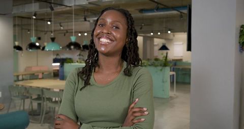 Confident african woman smiling with arms crossed in modern coworking space