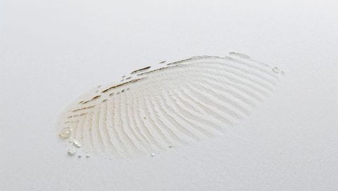 Dusty fingerprint impression revealing radial ridges with water droplets macro closeup