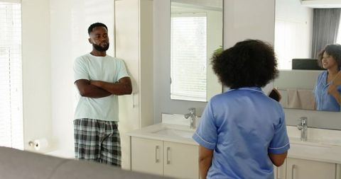 Black couple standing at double vanity sharing morning routine in bright bathroom