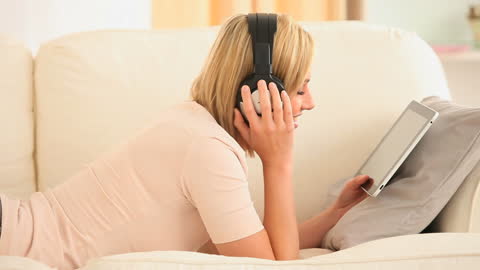 Woman Relaxing with Tablet and Headphones on Sofa