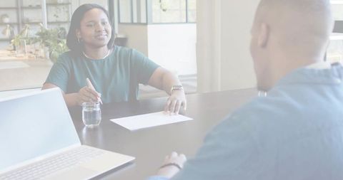 Holding pen and listening during one-on-one meeting at bright office table