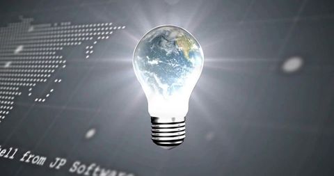Floating earth inside glowing light bulb emitting radiant halo over digital world map