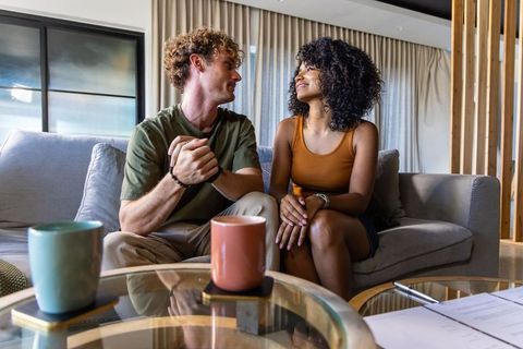 Interracial young couple sharing intimate moment on sofa in modern bright cozy living room
