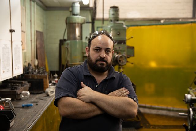 Portrait of a male factory worker standing with his arms crossed - Download Free Stock Photos Pikwizard.com