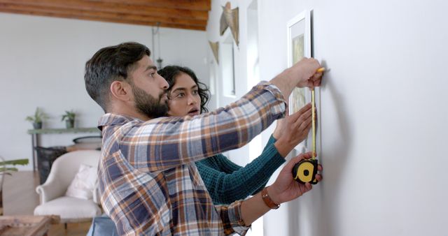 Couple Hanging Picture Frame on Wall with Measuring Tape in Modern Home Living Room - Download Free Stock Images Pikwizard.com