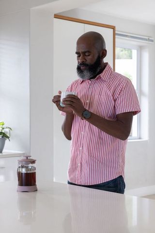 Senior African American Man Savoring Morning Coffee in Modern Kitchen