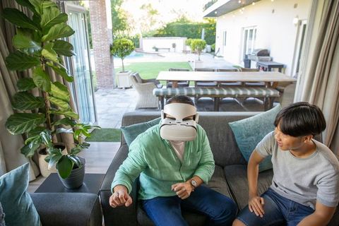 Father Enjoying Virtual Reality at Home with Curious Daughter