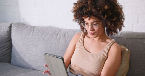 Woman Enjoying Leisure Reading on Tablet in Comfortable Home Setting