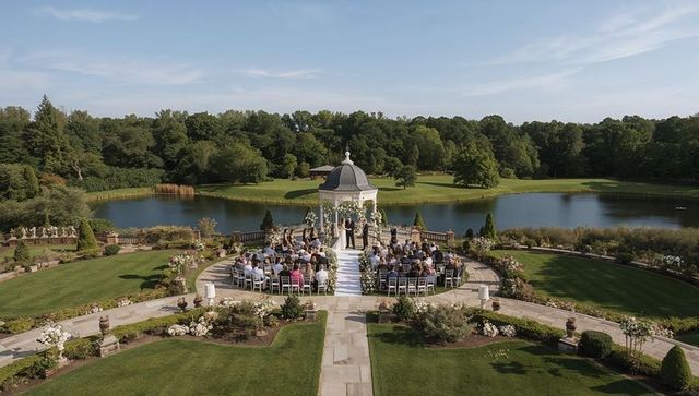 Couple exchanging vows at lakeside gazebo during elegant outdoor wedding ceremony