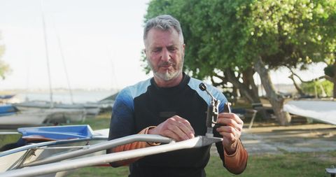 Senior man preparing rowing boat in scenic lakeside area