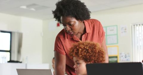 African American Teacher Guiding Teen Student on Laptop in Classroom for Digital Learning