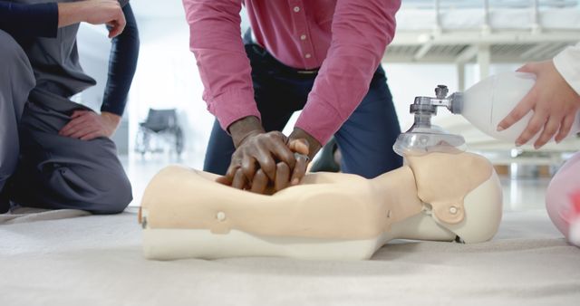 Medical professionals demonstrating CPR on a manikin in a training session. They are performing chest compressions and using medical equipment to ensure proper technique. This can be used to illustrate medical training, emergency response preparation, lifesaving techniques, and healthcare education. Suitable for websites, brochures, training manuals, and educational content focused on first aid and medical training.