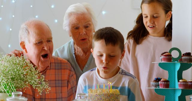 Front view of Caucasian multi-generation family celebrating birthday of their grandson in a comfortable home. Boy blowing out candles on birthday cake 4k