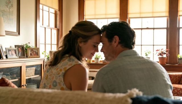 Sunlit intimate moment of couple touching foreheads on cozy sofa in plant-filled living room