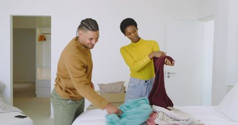 Couple Organizing Laundry Together in Bedroom