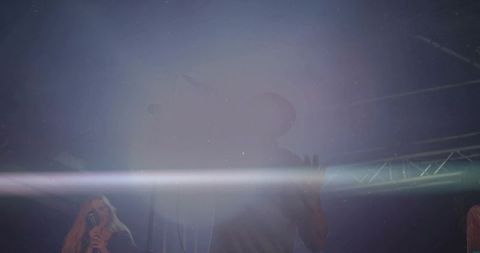 Silhouetted singer performing on hazy stage with vintage mic and dramatic light streak