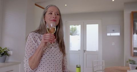 Senior Woman Enjoys Glass of Wine in Bright Kitchen Setting - Download Free Stock Images Pikwizard.com
