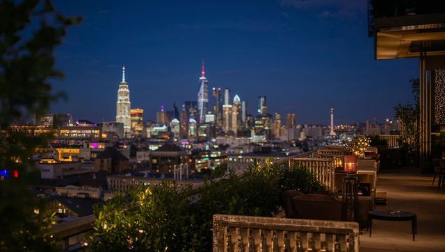 Rooftop terrace overlooking illuminated skyline at dusk with lantern-lit seating
