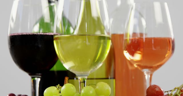 Glasses of red, white, and rosé wine are paired with clusters of green and red grapes, with copy space. A celebration of wine culture, this setup is perfect for showcasing different wine varieties and their complementary fruits.