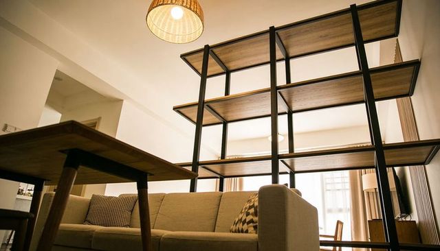 Mid-century modern living space with open wood and metal shelving divider, cozy sofa