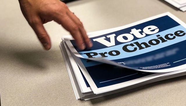 Hand Turning Vote Pro Choice Flyers on Tabletop for Grassroots Campaign and Advocacy Materials