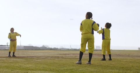 Female softball team practicing on field in sunlight