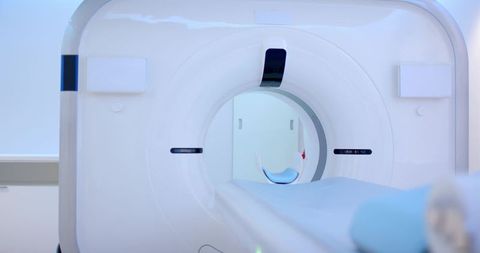 Modern ct scanner bore featuring sliding patient table and blue headrest in clinical suite