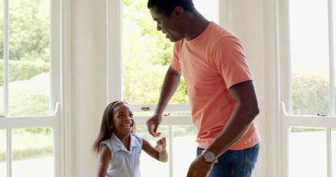 Father and Daughter Joyfully Dancing at Home by Bright Window