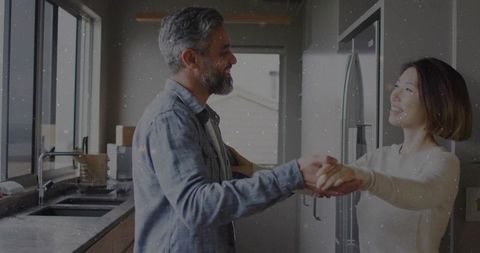 Mature Couple Dancing in Modern Kitchen with Joyful Expressions
