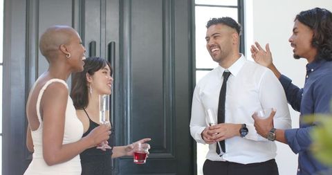 Smiling diverse professionals celebrating with cocktails in elegant foyer by double doors
